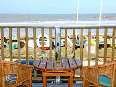 a wooden table and chairs on a balcony with the beach at Trysor Y Mor in Borth