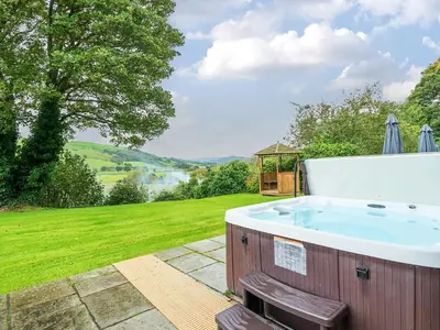 a jacuzzi tub in a garden with a view at Old Rectory Cottages in Aberhafesp