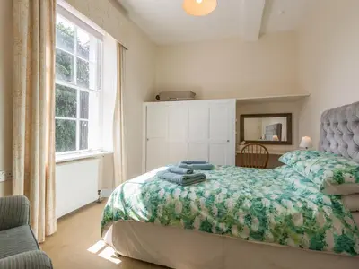 a bedroom with a bed with a green blanket and a window at The Old Schoolhouse and Cottage in Bishops Castle