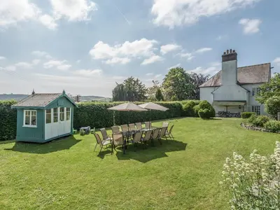 a garden with a table and chairs and a house at The Old Schoolhouse and Cottage in Bishops Castle