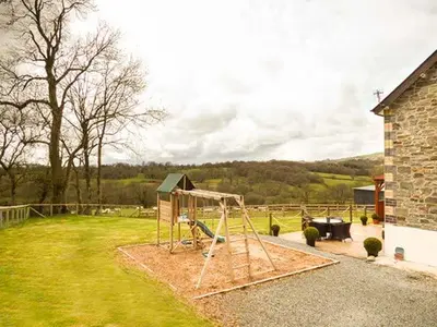 a playground in a yard next to a house at Cwmcelyn in Nantmel
