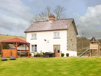 a large white house with a playground in a yard at Cwmcelyn in Nantmel