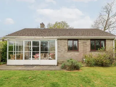 a house with a conservatory with a dog inside at Bryn yr Haf in Llanfair Clydogau