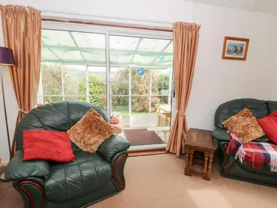 a living room with two leather chairs and a window at Bryn yr Haf in Llanfair Clydogau
