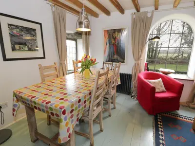 a dining room with a table and a red chair at Beudy Dolpebyll in Llangadfan