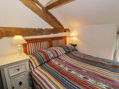 a bedroom with a bed with a colorful blanket on it at Beudy Dolpebyll in Llangadfan