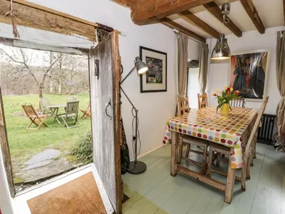a dining room with a table and a window at Beudy Dolpebyll in Llangadfan