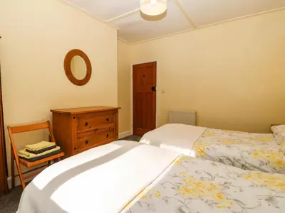 a bedroom with two beds and a dresser and a mirror at Bron Aber in Arthog