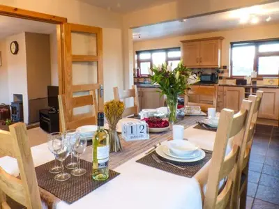 a dining room with a table with plates and wine glasses at Tynddol Bungalow in Llanbadarn-fynydd