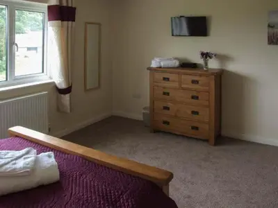 a bedroom with a bed and a dresser and a window at Cwmgilla Farm in Knighton