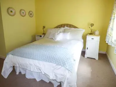 a bedroom with a large bed with white sheets and pillows at Crud-y-Barcud in Pumpsaint
