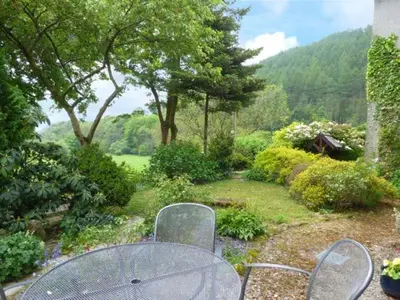 a patio with a table and chairs in a garden at Crud-y-Barcud in Pumpsaint