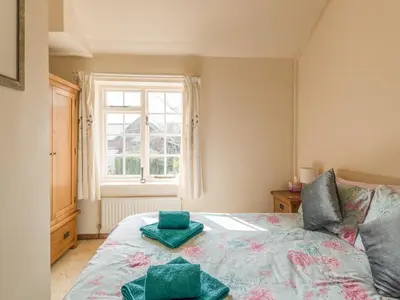a bedroom with a bed with two green cushions on it at Old Town Cottage in Ludlow