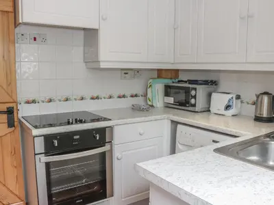 a kitchen with white cabinets and a stove top oven at Tuc - Tin in Clun