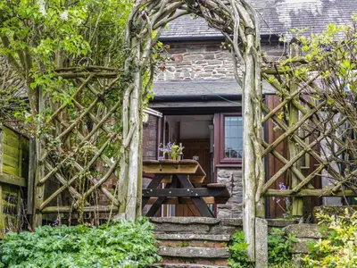 an archway leading into a cottage with a picnic table at Tuc - Tin in Clun