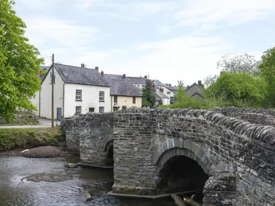 an old stone bridge over a river in a village at Tuc - Tin in Clun
