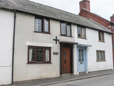a white house with a blue door on a street at Tuc - Tin in Clun