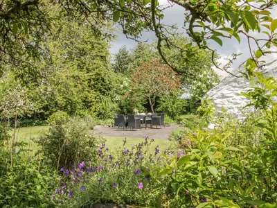 a garden with a table and chairs and flowers at Penymaes in Chirk