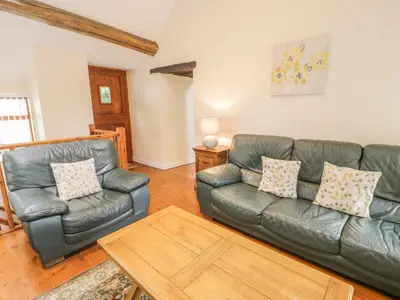 a living room with a leather couch and a table at Hendoll Cottage 1 in Fairbourne