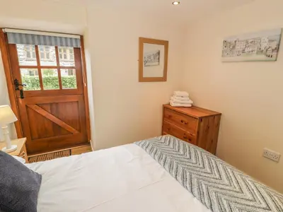 a bedroom with a bed and a wooden door at Hendoll Cottage 1 in Fairbourne