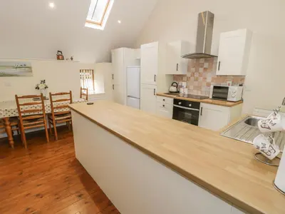 a kitchen with white cabinets and a counter top at Hendoll Cottage 2 in Fairbourne