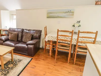 a living room with a leather couch and a table at Hendoll Cottage 2 in Fairbourne