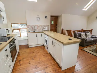 a kitchen with white cabinets and a counter top at Hendoll Cottage 2 in Fairbourne
