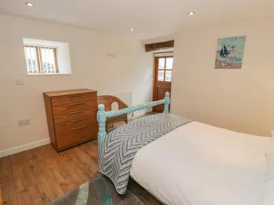 a bedroom with a bed and a wooden dresser at Hendoll Cottage 2 in Fairbourne
