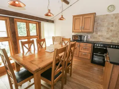 a kitchen with a wooden dining room table and chairs at Hendoll Barn in Fairbourne