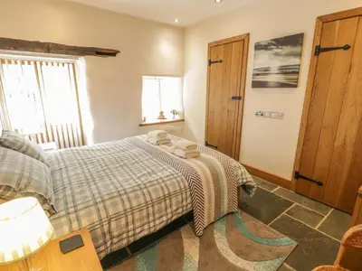 a bedroom with a bed with a blanket on it at Hendoll Barn in Fairbourne
