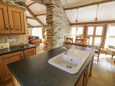 a kitchen with a sink in the middle of a room at Hendoll Barn in Fairbourne