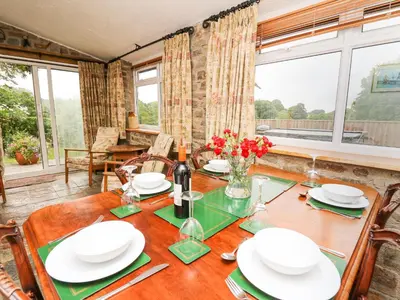 a dining room with a table and a large window at Holly Farm Cottage in Newbridge on Wye