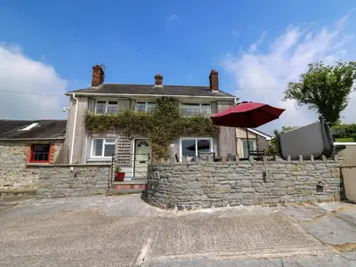 a house with a stone wall and an umbrella at Aberdauddwr in Llanwnen
