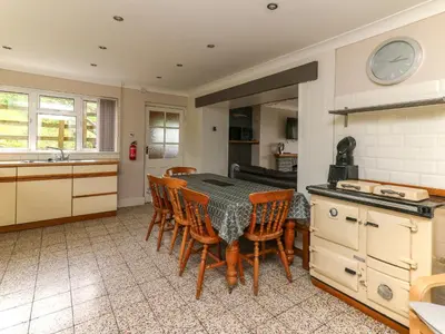 a kitchen with a table and chairs in a room at Aberdauddwr in Llanwnen