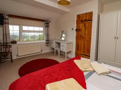 a bedroom with a bed with a red rug and a window at Aberdauddwr in Llanwnen
