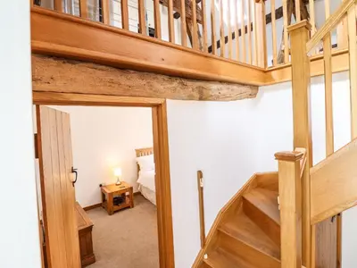 a wooden staircase in a bedroom with a bed at Ysgubor Las in Dolgellau