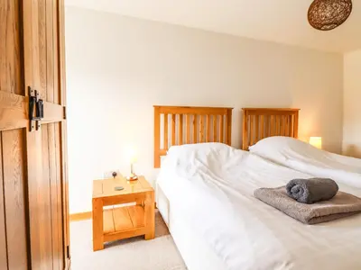 a bedroom with a white bed and a table with a night stand at Ysgubor Las in Dolgellau