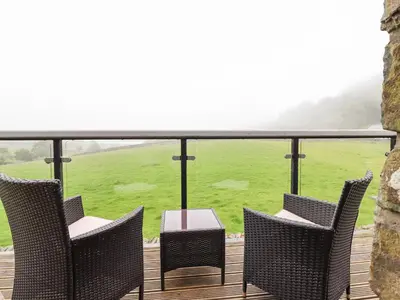 a deck with chairs and a table and a green field at Ysgubor Las in Dolgellau