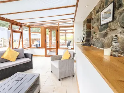 a living room with couches and a stone wall at Ysgubor Las in Dolgellau