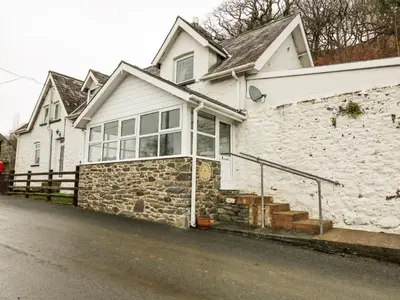 a white house with a stone wall at Tanyrallt Farm in Beulah