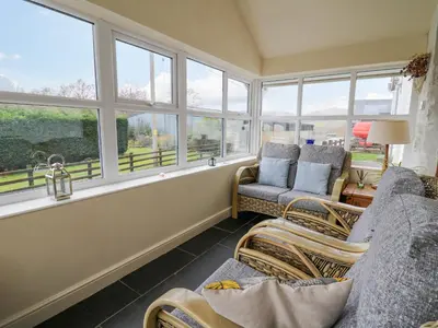 a living room with two chairs and windows at Tanyrallt Farm in Beulah