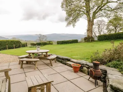 a patio with a table and benches and a field at Groes Lwyd in Gwyddelwern