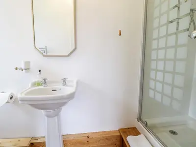 a white bathroom with a sink and a shower at Groes Lwyd in Gwyddelwern