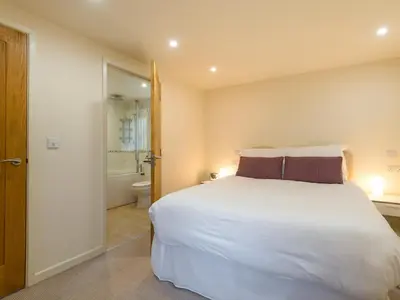 a bedroom with a large white bed and a bathroom at Bishop's Castle Barn in Bishops Castle
