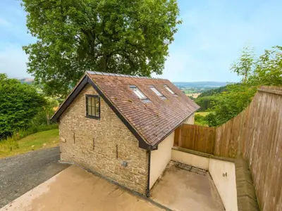 a small brick building with a wooden fence at Bishop's Castle Barn in Bishops Castle