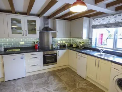 a kitchen with white cabinets and a large window at Maerdy Cottage in Bettws Gwerfil Goch