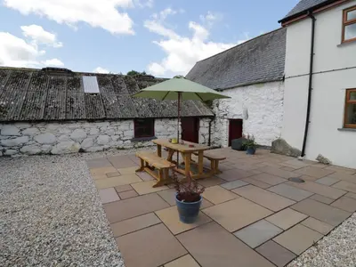 a patio with a wooden table and an umbrella at Maerdy Cottage in Bettws Gwerfil Goch