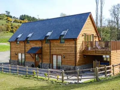 a large wooden house with a porch and a deck at Brynhir Farm in Llandrindod Wells