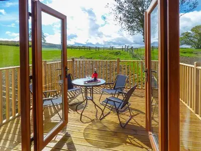 a patio with a table and chairs on a deck at Brynhir Farm in Llandrindod Wells