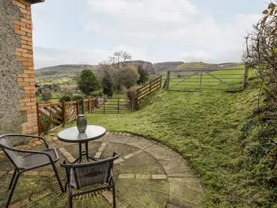 a table and chairs on a patio with a view of a field at Peniarth in Pen-y-bont-fawr
